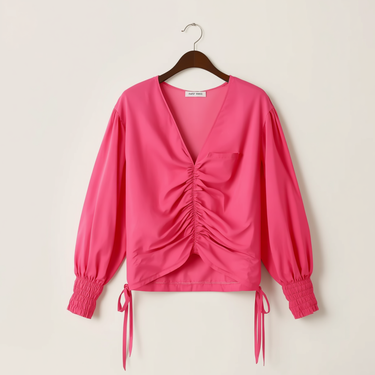 Blouse rose vif à manches longues avec col V, devant froncé et liens latéraux